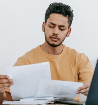 Profesional revisando ofertas de empleo en laptop y documentos