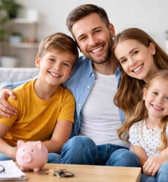 Familia feliz de cuatro personas sonriendo en el salón de casa, transmitiendo seguridad y bienestar financiero