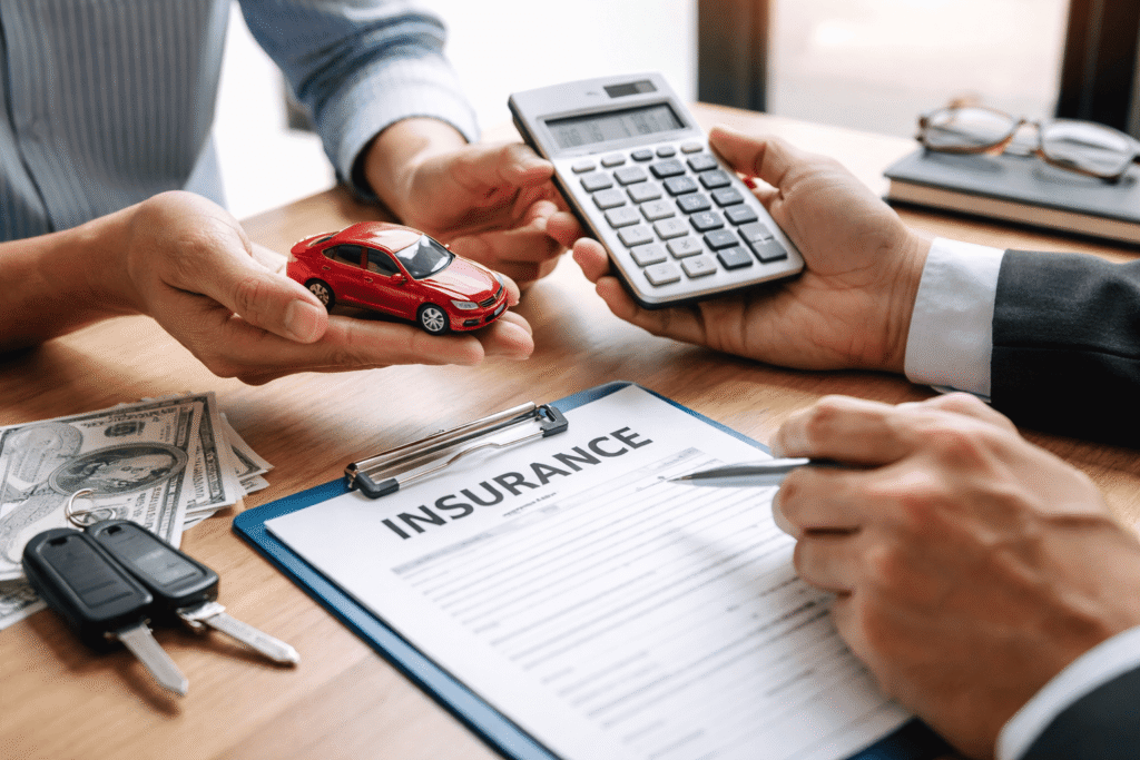 Personas negociando el precio de un seguro de coche con calculadora, llaves del coche y contrato de seguro sobre la mesa