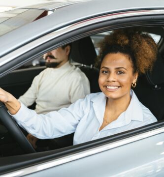 Pareja sentada revisando documentos de seguro de auto, planificando cómo encontrar un seguro de coche barato
